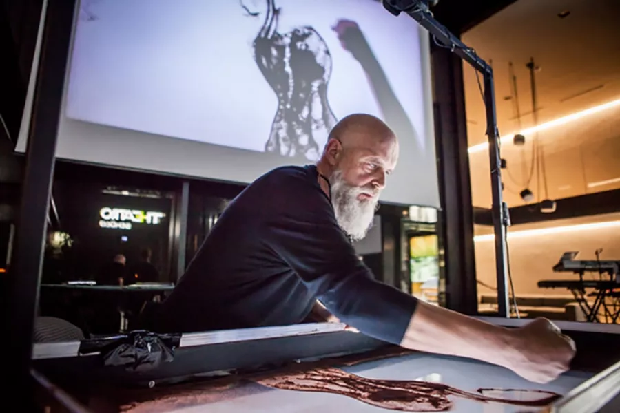 L’artista Beppe Brondino alla lavagna luminosa mentre crea con la sand art