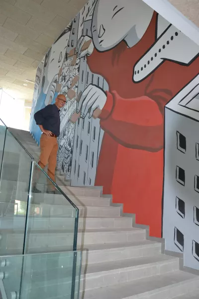 Il sindaco, Ezio Donadio, sulla scala dell'atrio della nuova scuola, dominato dal murales dell’artista Millo