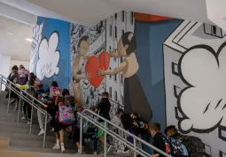 Gli alunni risalgono il grande scalone decorato con il murales dell'artista Millo