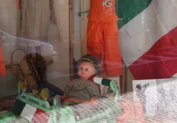 Bambolotto conla piuma sul cappello, nel negozio di abbigliamento per l'infanzia