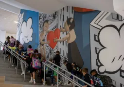 Gli alunni risalgono il grande scalone decorato con il murales dell'artista Millo